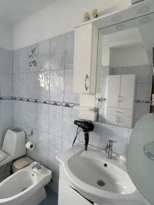 un bagno con lavandino, WC e specchio di At Teo's a Durrës Altre 12 foto