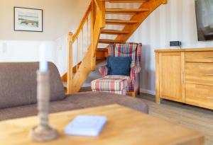 ein Wohnzimmer mit einer Treppe und einem Stuhl in der Unterkunft Ferienwohnung Lachmöwe in Norddorf