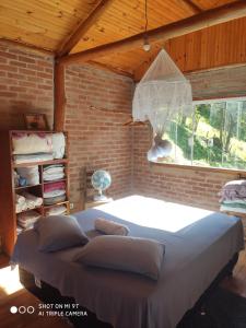 a bedroom with a large bed in a brick wall at Chalés do GreenGo in Santo Antônio do Pinhal