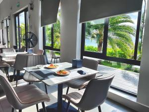 a restaurant with a table and chairs and a large window at Du Parc Mũi Né Resort - Sᴀɴᴅ ᴅᴜɴᴇ & ᴏᴄᴇᴀɴ ᴠɪᴇᴡ in Mui Ne