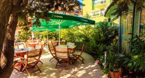 a restaurant with tables and chairs and a green umbrella at Hotel Boomerang - Sunny Beach in Sunny Beach