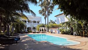 a swimming pool in front of a building with palm trees at Dulaa Deema Residence Brufut Heights in Trankill