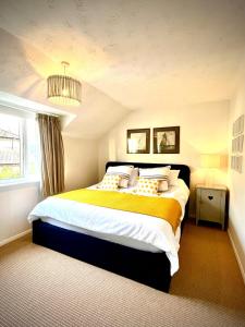 a bedroom with a large bed with yellow and white sheets at Gorgeous Comfy Cottage Walking Birdwatching Paddle Boarding and Seafood on the Doorstep in West Mersea