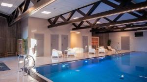 a large swimming pool with white chairs and a table at Vakker leilighet i Åros in Søgne