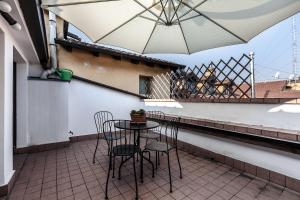 una mesa y sillas en un balcón con sombrilla en MilanRentals - Palazzi Apartment, en Milán