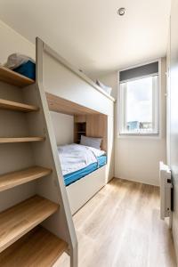 a small bedroom with a bunk bed and a window at Düne 46 in Scharbeutz