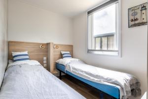 two beds in a room with a window at Düne 46 in Scharbeutz