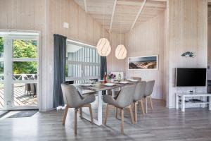 une salle à manger avec une table, des chaises et une télévision dans l'établissement Hus Lykke - Strandpark 38, à Grömitz