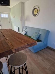 a living room with a blue couch and a wooden table at Maisonnette indépendante in Lœuilley +3 photos