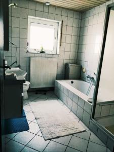 a bathroom with a tub and a toilet and a window at 76 qm Whg im EG Haus-Wohlfühloase vor der Haustür in Gladenbach