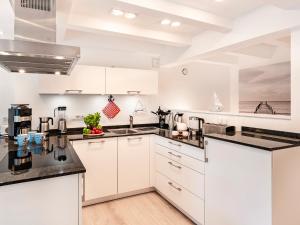 a kitchen with white cabinets and black counter tops at FeWo Prora - Kapitänskajüte in Binz +14 photos