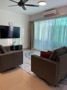 a living room with two couches and a flat screen tv at Bunga Home with swimming pool access in Lahad Datu