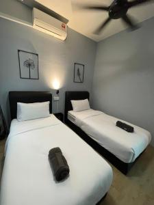 a room with two beds with white sheets and a bag on them at Bunga Home with swimming pool access in Lahad Datu