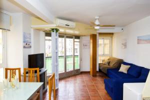 Una sala de estar con un sofá azul y un televisor. en Águilas Centro Playa La Colonia, en Águilas