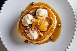 a plate with a stack of pancakes with bananas and nuts at Hotel M Soleil - Montpellier Centre Saint Roch in Montpellier +90 photos