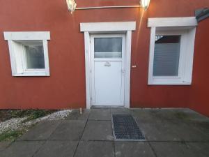 a red building with a white door and two windows at Ferienwohnung "Unner Deck" in Sahrensdorf +2 photos