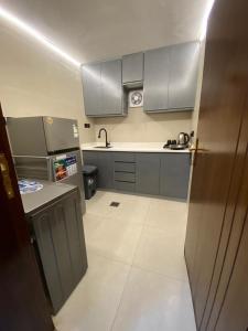 a kitchen with gray cabinets and a white tile floor at غزالي سويتس ghzali suites in Al Madinah +14 photos