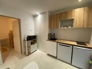 a kitchen with white counters and wooden cabinets at Isolella à 50 m de la plage in Pietrosella