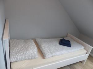 a white crib with two pillows and a blue hat on it at Ferienhaus Sonnenblick in Walsrode