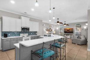 a kitchen with white cabinets and a island with bar stools at Miramar Magic in Destin