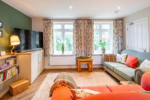 a living room with a couch and a tv at Brackenhurst Cottage by Big Skies Cottages in West Runton