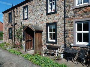 a brick building with a wooden door and a bench at Rose cottage on the peaceful solway coast in Port Carlisle
