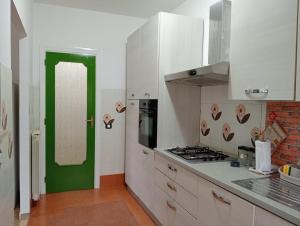 a kitchen with white cabinets and a green door at Casa Toledo in Torvaianica +4 photos