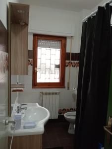 a bathroom with a sink and a toilet and a window at Casa Toledo in Torvaianica