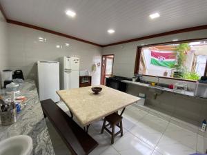 Casa Temporada Maria Antônia في باراتي: مطبخ مع طاولة وثلاجة