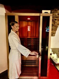 a woman in a white robe opening a refrigerator at Celje Spa Apartment in Celje