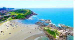 un grupo de personas en una playa cerca del océano en Hostel Oásis, en Itanhaém