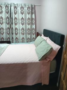 een bed met twee kussens erop met een gordijn bij Casa Com 2 quartos, Garagem Ar tv in Foz do Iguaçu