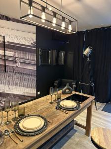 a wooden table with plates and glasses and a lamp at SPA Loft & Dentelle in Caudry +10 photos
