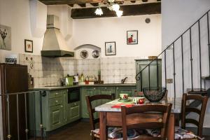 a kitchen with green cabinets and a table and chairs at PULCINELLA appartamento tipico centro storico in Montepulciano
