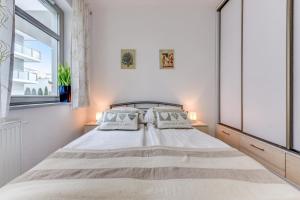 a white bedroom with a large bed with two pillows at Aqua by Grand Apartments in Gdańsk