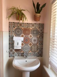 a bathroom with a sink and a tiled wall at The Boho - 4 min walk to beach & town in Bournemouth