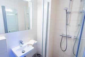 a white bathroom with a shower and a sink at Soldanella 6 by Alpenidyll Apartments in Ramsau am Dachstein +4 photos