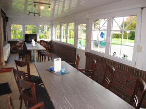 Un comedor con mesas y sillas y ventanas. en Ferienhaus INGE MOOR203 ruhig gelegen im Hinterland der NORDSEE, en Südbrookmerland 17 fotos más
