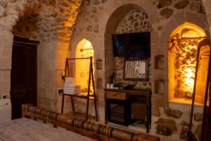 a bedroom with a stone wall with a tv and a mirror at Marvel Hotel Mardin in Mardin