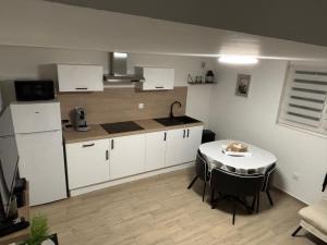 una cucina con tavolo e una cucina con armadietti bianchi di Petite maison au calme a Pont-de-Larn