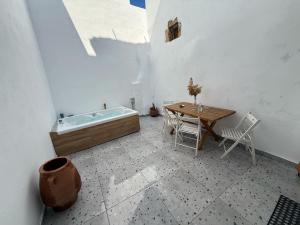 a bathroom with a tub and a table with chairs at Philoxenia traditional house private jacuzzi in Palaiólimnos +49 photos