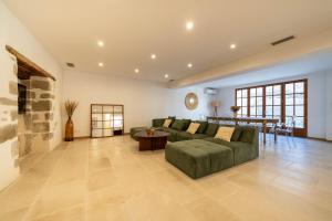 ein großes Wohnzimmer mit einem grünen Sofa und einem Tisch in der Unterkunft Exceptionnel - Couvent entièrement rénové - classé Patrimoine - Piscine, au calme et à 100 m du coeur de l'Isle in LʼIsle-sur-la-Sorgue