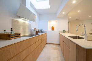 eine große Küche mit Holzschränken und einem Waschbecken in der Unterkunft Exceptionnel - Couvent entièrement rénové - classé Patrimoine - Piscine, au calme et à 100 m du coeur de l'Isle in LʼIsle-sur-la-Sorgue