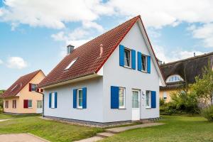 a white house with blue windows and a brown roof at A 5 Ferienhaus Triton in Gramkow