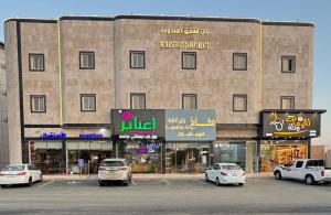 a large building with cars parked in a parking lot at رتان للشقق المخدومة in Khamis Mushayt