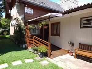 Casa con porche de madera con sombrilla en Pousada Genial, en Gramado