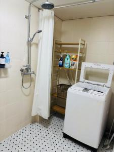 a shower in a bathroom with a washing machine in it at Travel Apartment in Seoul