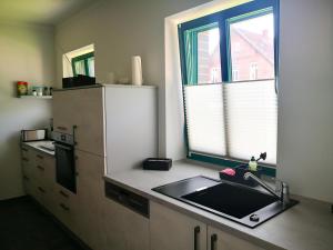 a kitchen with a sink and a refrigerator and a window at Auszeithof Otersen - Ferienwohnung 1 in Kirchlinteln