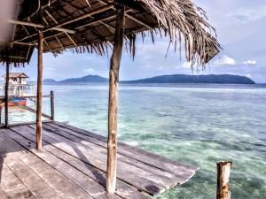 a wooden dock with a thatched roof over the water at Baracuda Homestay in Airborei