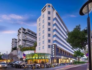 温州市にあるWenzhou wumajie all-weather hotel shamao river branch - located in the city center pedestrian street with breakfast coffee afternoon tea free laundry drying service free gym free daily necessities free wifi tourist attractions hotel recommendationの通り沿いにある背の高い白い建物